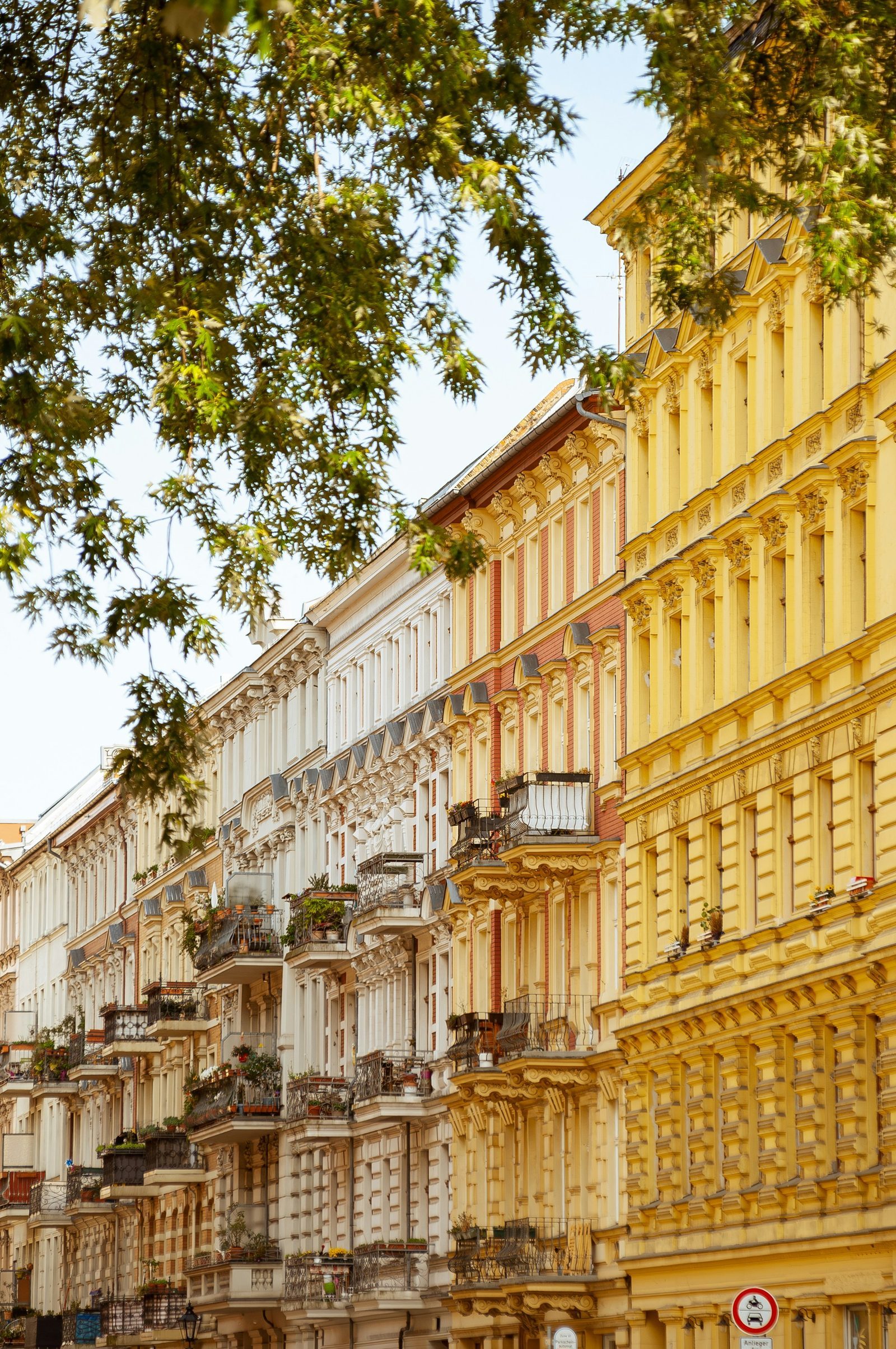 A row of yellow Altbau facades against a clear Berlin sky