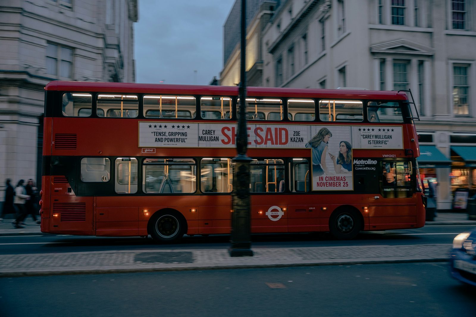 A red double-decker bus on a London street at night